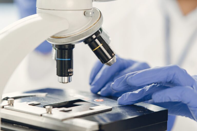 Close-up view of a scientist examining a specimen under a microscope in a laboratory.